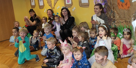 Powiększ grafikę: Dzieci wraz z nauczycielkami siedzą na podłodze i kibucują klaszcząc