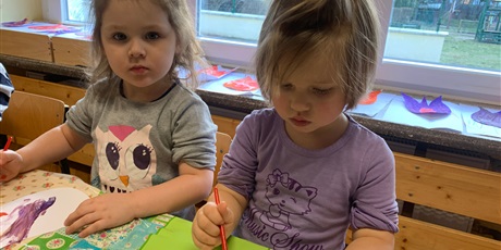 Powiększ grafikę: Dwie dziewczynki siedzą przy stole. Malują farbami