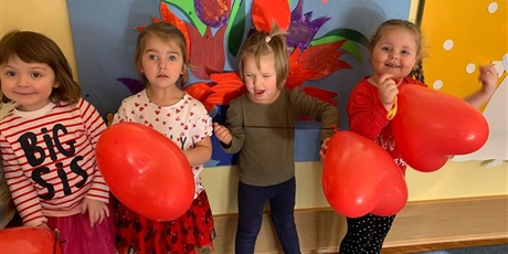 Powiększ grafikę: Cztery dziewczynki pozują. W ręku trzymają czerwone balony w kształcie serca