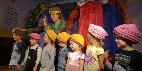 Powiększ grafikę: Grupa dzieci stoi z turbanami na głowie. Aktor dotyka głowy chłopca