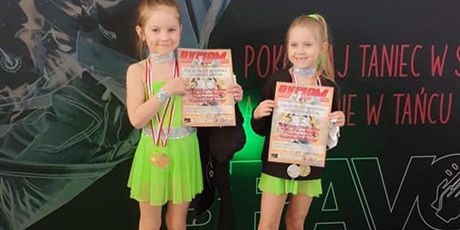 Powiększ grafikę: Dwie dziewczynki w zielonych sukienkach trzymają dyplomy