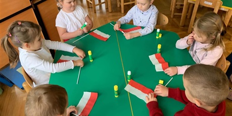 Powiększ grafikę: Ujęcie na stół, na którym leżą przygotowane flagi Polski
