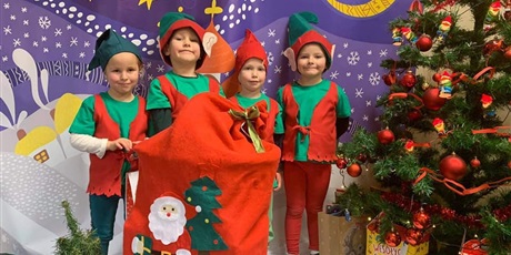 Powiększ grafikę: Czwórka dzieci przebrana jest za elfy. Po środku stoi czerwony worek