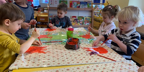 Powiększ grafikę: Piątka dzieci siedzi przy stole. Malują farbami