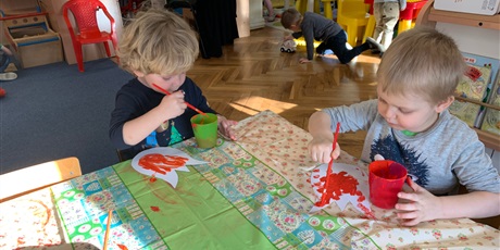 Powiększ grafikę: Dwójka chłopców siedzi przy stole. Malują farbami