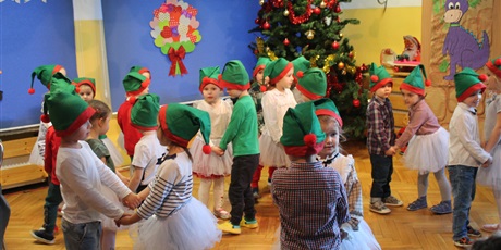 Powiększ grafikę: Dzieci w czerwono-zielonych czapkach tańczą w parach