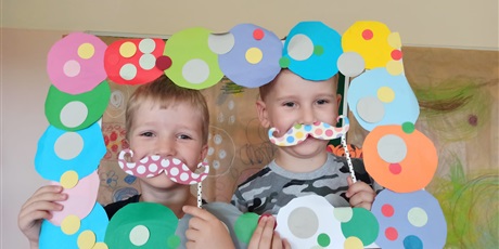 Powiększ grafikę: Dwójka chłopców pozuje do zdjęcia trzymając papierowe wąsy