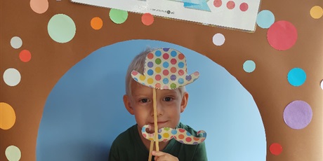 Powiększ grafikę: Chłopiec pozuje do zdjęcia z papierowym kapeluszem i wąsami