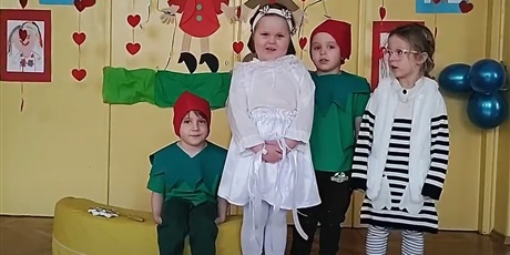 Powiększ grafikę: Trójka dzieci stoi. Dziewczynki są ubrane w biało-czarne stroje. Dwójka chłopców ma zielone koszulki i czerwone czapki