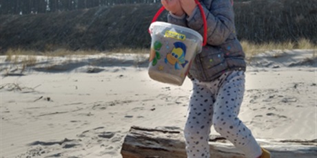 Powiększ grafikę: Dziecko trzyma w rękach wiaderko z piaskiem