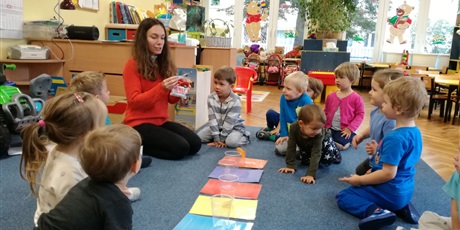 Powiększ grafikę: Nauczycielka pokazuje dzieciom czerwony przedmiot