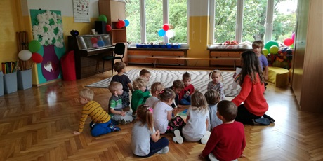 Powiększ grafikę: Dzieci z nauczycielką siedzą w kole na sali gimnastycznej