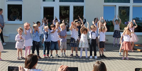 Powiększ grafikę: Grupa dzieci klaszcze unosząc ręce do góry