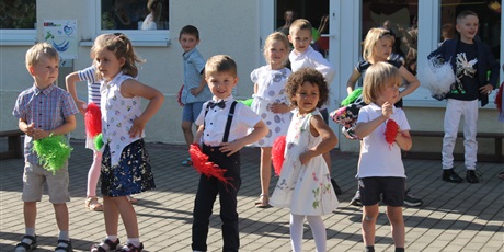 Powiększ grafikę: Dzieci tańczą trzymając w ręku czerwone i zielone pompony