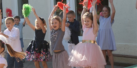 Powiększ grafikę: Dzieci podnoszą ręce do góry trzymając w ręku kolorowe pompony