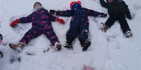 Powiększ grafikę: Trójka dzieci leży na śniegu