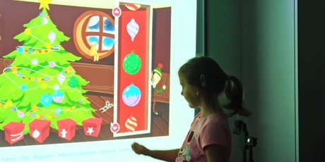 Powiększ grafikę: Dziewczynka rozwiązuje zadanie z użyciem tablicy multimedialnej